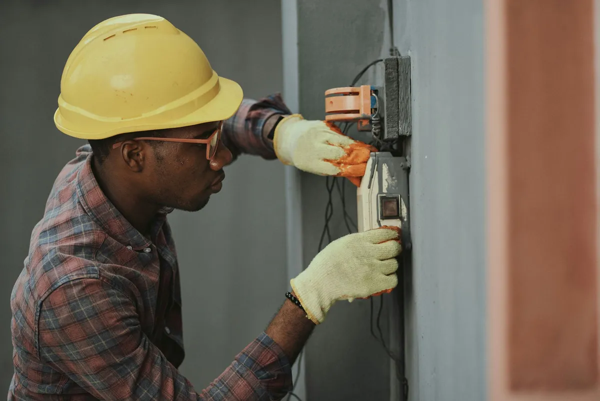 Electrician wiring an exterior electrical service mast on a house — illustrative stock photo, not an actual East Valley job site